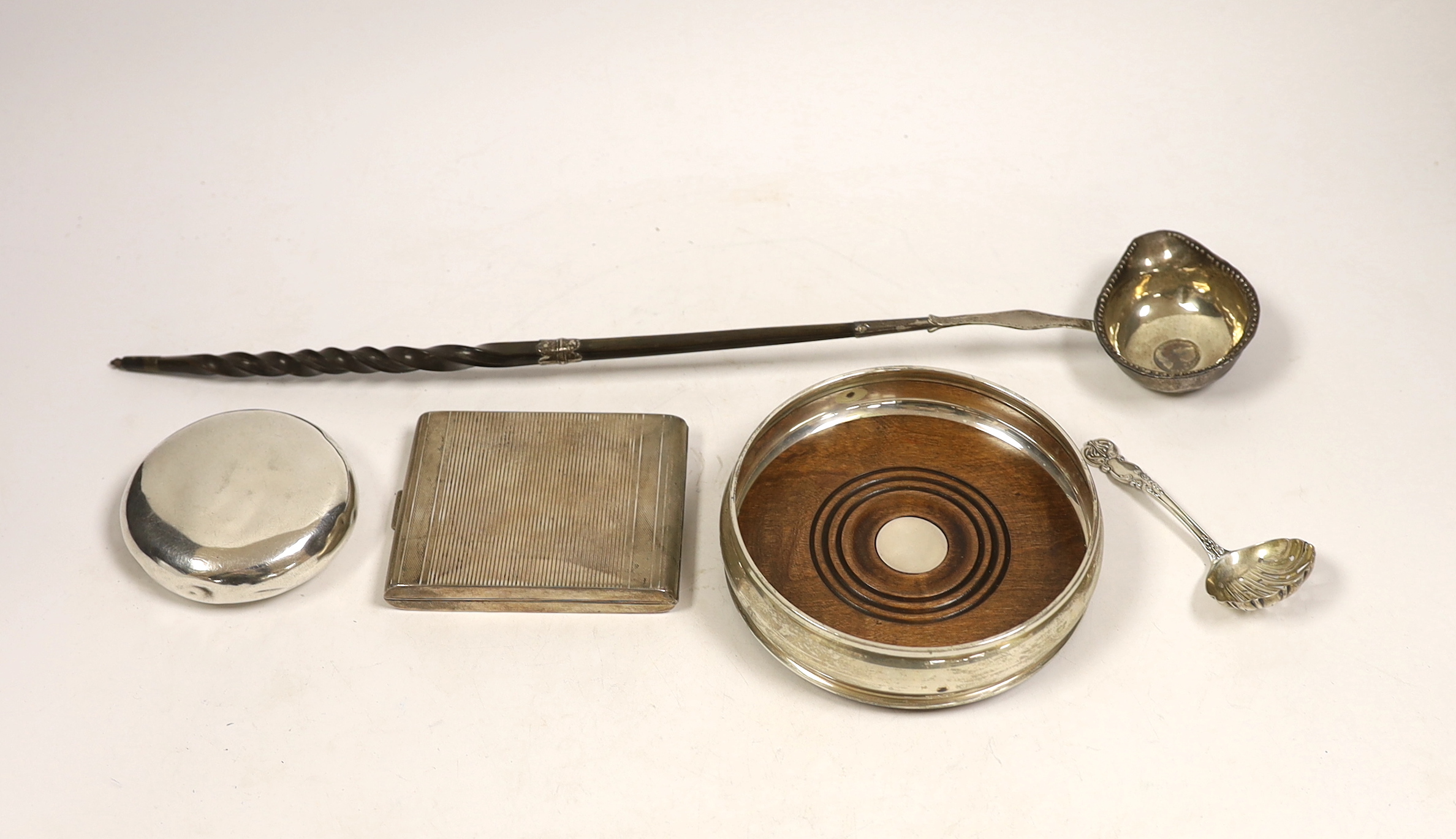 A modern silver mounted wine coaster, a silver sifter spoon, sterling cigarette case, silver tobacco box and a white metal toddy ladle with baleen handle.